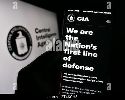 Personne tenant un téléphone portable avec le site de la Central Intelligence Agency (CIA) des États-Unis devant le sceau. Concentrez-vous sur le centre de l'écran du téléphone. Banque D'Images