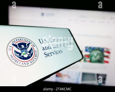 Téléphone portable avec sceau de l'agence américaine Citizenship and Immigration Services (USCIS) devant le site Web. Effectuez le focus sur la gauche de l'écran du téléphone. Banque D'Images