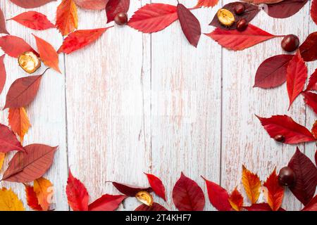 Feuilles d'automne et châtaignes sur fond en bois. Pose à plat, vue de dessus, espace de copie. Banque D'Images