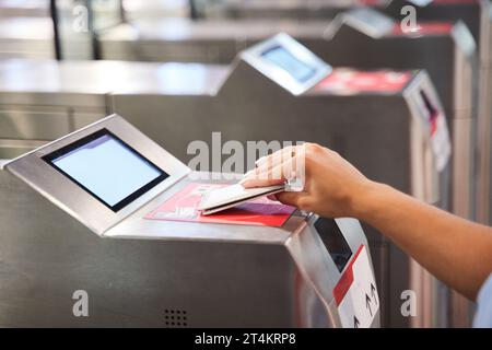 gros plan de la main d'une personne méconnaissable avec une carte d'accès entrant par les portes de sécurité d'un système de transport en commun. Banque D'Images