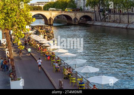 Quai animé le long de la Seine avec des gens profitant du temps dehors, se détendre et courir, en été, centre-ville de Paris, France Banque D'Images