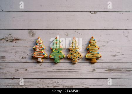 Biscuits d'arbre de Noël avec glaçage coloré reposent sur une table en bois clair Banque D'Images