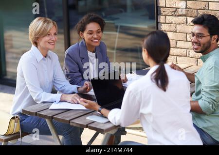 Équipe créative collaborant sur le projet pendant la réunion dans un café en plein air. Conception de l'entreprise Banque D'Images