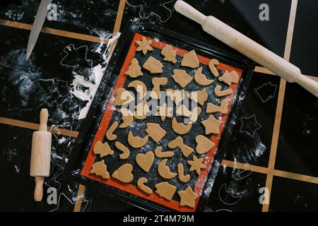 Des biscuits de Noël crus de différentes formes reposent sur un plateau sur la table Banque D'Images