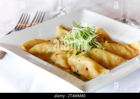 Assiette de boulettes pierogies en sauce dans un restaurant ou un café, sur une assiette Banque D'Images