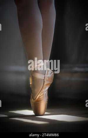 Danseur de ballet sur le point, portant des chaussures de pointe dans l'ombre et le fond mis en évidence Banque D'Images