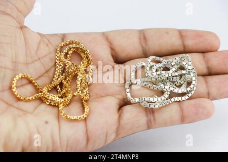 Chaînes en argent réel et or tenu dans la main. Accessoires de mode de luxe Banque D'Images