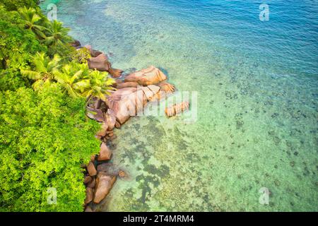 Drone oeil d'oiseau de la plage de baie lazare, pierres de granit, eau turquoise, cocotiers, journée ensoleillée, Mahe Seychelles Banque D'Images