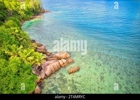 Drone oeil d'oiseau de la plage de baie lazare, pierres de granit, eau turquoise, cocotiers, journée ensoleillée, Mahe Seychelles Banque D'Images