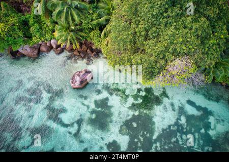 Drone oeil d'oiseau de la plage de baie lazare, pierres de granit, eau turquoise, cocotiers, journée ensoleillée, Mahe Seychelles Banque D'Images