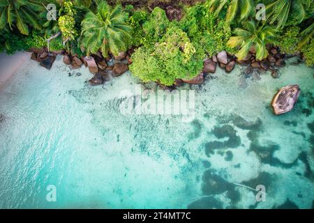 Drone oeil d'oiseau de la plage de baie lazare, pierres de granit, eau turquoise, cocotiers, journée ensoleillée, Mahe Seychelles Banque D'Images