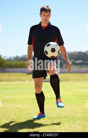 Il peut garder cette balle en l'air pendant des heures. un jeune footballeur rebondissant une balle sur son genou. Banque D'Images