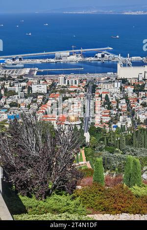 Haïfa, Israël - 22 octobre 2023 : Panorama des jardins Bahai et du quartier résidentiel avec le port en arrière-plan du ciel bleu avec des nuages. Banque D'Images