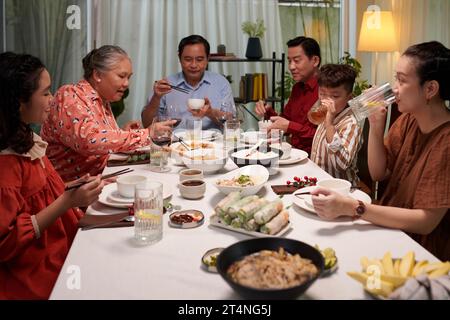 Grande famille appréciant des plats de la cuisine vietnamienne au dîner Banque D'Images