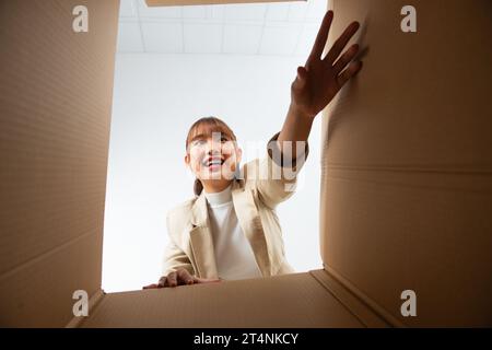 Jeune femme de l'ouverture d'une boîte de carton, réinstallation et déballage concept Banque D'Images