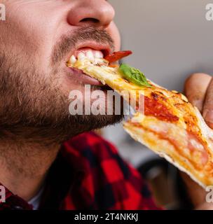 Homme barbu mangeant une pizza photographie rapprochée. Banque D'Images