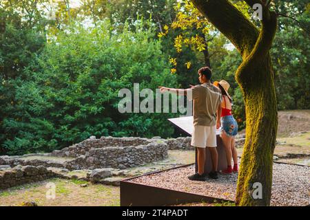 jeune couple touristique multiracial soulignant des vestiges archéologiques au coucher du soleil d'été Banque D'Images