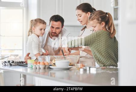 Tout le monde a un tour à fouetter. une famille cuisinant ensemble dans la cuisine. Banque D'Images