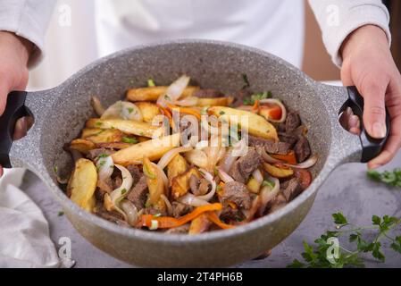 Mains tenant une cocotte avec un plat typiquement péruvien appelé Lomo saltado. Banque D'Images