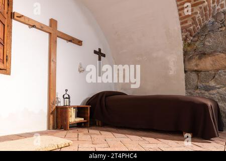 Avila, Espagne, 08.10.21. Cellule monastique ascétique dans le musée et la maison de Santa Teresa d'Avila, vue intérieure de la chambre de Saint avec lit simple et croix. Banque D'Images