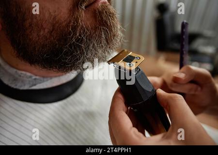 Gros plan du coiffeur à l'aide du rasoir pour raser la barbe du client Banque D'Images
