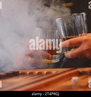 Les gens boivent du whisky, fument du narguilé et jouent au backgammon au bar. Couple se reposant ensemble après une dure journée. Banque D'Images