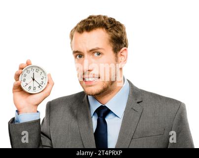 HES toujours sur l'horloge. un homme d'affaires tenant une horloge contre un fond de studio. Banque D'Images