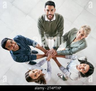 Je ne souhaite pas que ce soit plus facile. J'aimerais que vous soyez mieux. Prise de vue en grand angle d'un groupe de jeunes hommes d'affaires se joignant main dans la main dans un bureau moderne. Banque D'Images