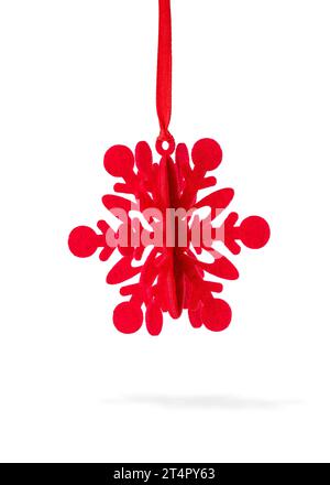 Ornement de Noël rouge attaché avec ruban de velours rouge sur fond blanc. Banque D'Images