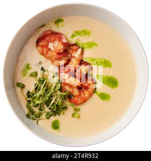 Délicieuse soupe crémeuse au fromage avec crevettes grillées et légumes frais, servie dans un bol blanc. Isolé sur fond blanc Banque D'Images