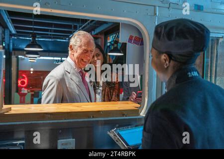 Le roi Charles III visite le stand Desi Loco Indian Street Food et commande un rouleau de saag paneer kathi et un samosa au poulet au beurre lors d’une visite à Nairobi Street Kitchen pour célébrer la scène culturelle et créative kenyane et rencontrer de jeunes créatifs, notamment des artisans, des créateurs de mode, des musiciens et des artistes, le deuxième jour de la visite d'État au Kenya. Date de la photo : mercredi 1 novembre 2023. Banque D'Images