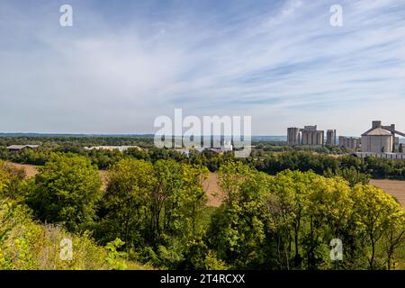 Arbres verdoyants dans la réserve naturelle de Thier de Lanaye dans la partie belge de Sint-Pietersberg, usine de ciment contre ciel bleu brumeux et horizon dans le backgr Banque D'Images