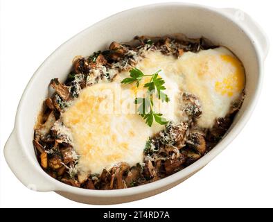 Délicieux œufs cuits au four avec des champignons servis dans un plat allant au four, isolé sur fond blanc. Banque D'Images