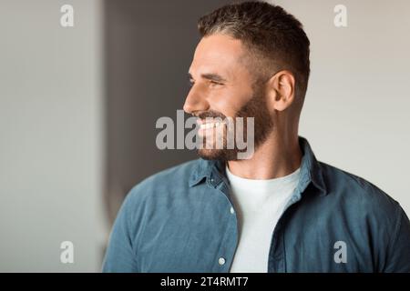 Joyeux homme d'âge moyen souriant tout en regardant de côté à l'intérieur Banque D'Images