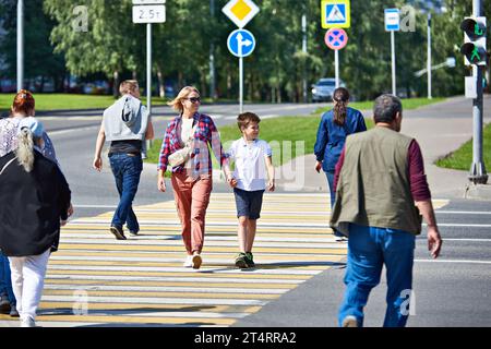 Une femme et un enfant traversent la route à un passage pour piétons Banque D'Images