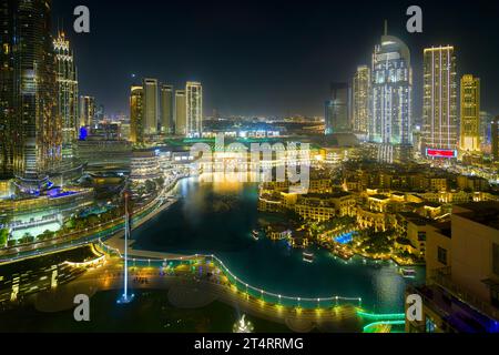 Les eaux de la fontaine de Dubaï entourées de bâtiments illuminés et le centre commercial de Dubaï la nuit au centre-ville de Dubaï, Émirats arabes Unis. Banque D'Images