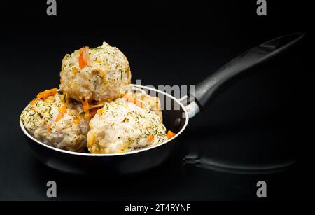 boulettes de viande de régime de poulet cuit dans une poêle, isolées sur un fond noir Banque D'Images