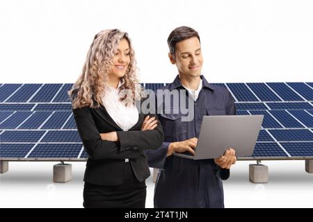 Femme d'affaires et un technicien regardant un ordinateur portable devant le photovoltaïque isolé sur fond blanc Banque D'Images