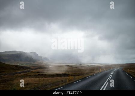 Une route à travers une friche rugueuse bordée de brouillard juste avant le début d'une forte pluie Banque D'Images