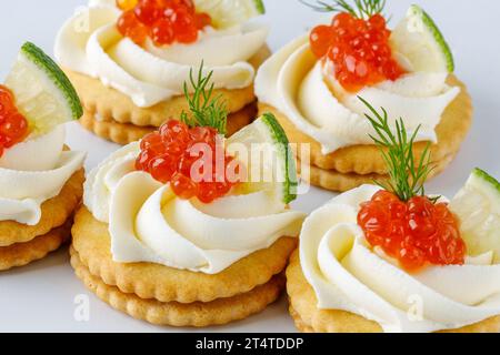 canapés au fromage à pâte molle et caviar rouge sur fond blanc Banque D'Images