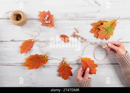 Guirlande maison de feuilles d'automne colorées avec des mains de femmes Banque D'Images