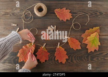 Guirlande maison de feuilles d'automne colorées avec des mains de femmes Banque D'Images