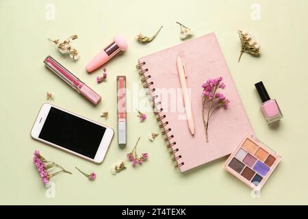 Composition avec téléphone portable moderne, produits de maquillage et belles fleurs de gypsophila sur fond beige Banque D'Images