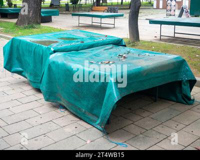 Tables de ping-pong recouvertes de bâche. Protéger la bouche de la pluie. Concept de fin d'été dans le parc. sport dans le parc. vacances à la station. Personne Banque D'Images