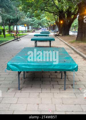 Tables de ping-pong recouvertes de bâche. Protéger la bouche de la pluie. Concept de fin d'été dans le parc. sport dans le parc. vacances à la station. Personne Banque D'Images