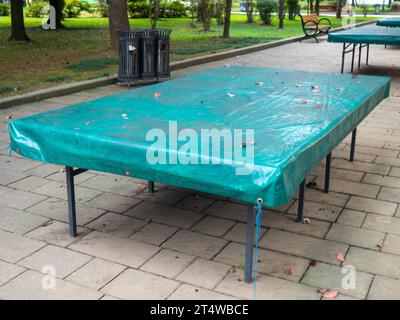 Tables de ping-pong recouvertes de bâche. Protéger la bouche de la pluie. Concept de fin d'été dans le parc. sport dans le parc. vacances à la station. Personne Banque D'Images