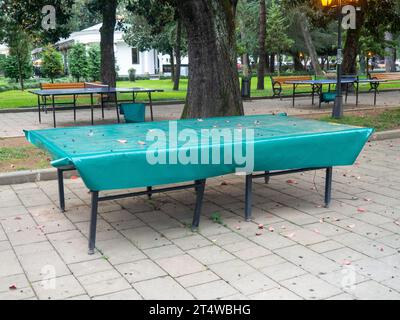 Tables de ping-pong recouvertes de bâche. Protéger la bouche de la pluie. Concept de fin d'été dans le parc. sport dans le parc. vacances à la station. Personne Banque D'Images