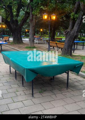 Tables de ping-pong recouvertes de bâche. Protéger la bouche de la pluie. Concept de fin d'été dans le parc. sport dans le parc. vacances à la station. Personne Banque D'Images