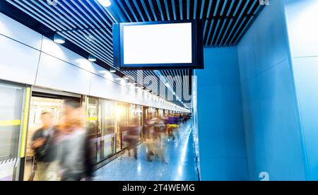 Panneau d'affichage vierge à un passage souterrain avec des passagers à mouvement flou en arrière-plan Banque D'Images