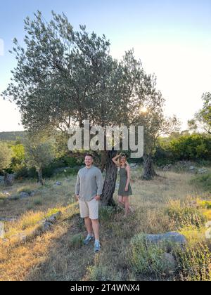 Homme souriant debout devant un arbre contre lequel une femme se penche Banque D'Images